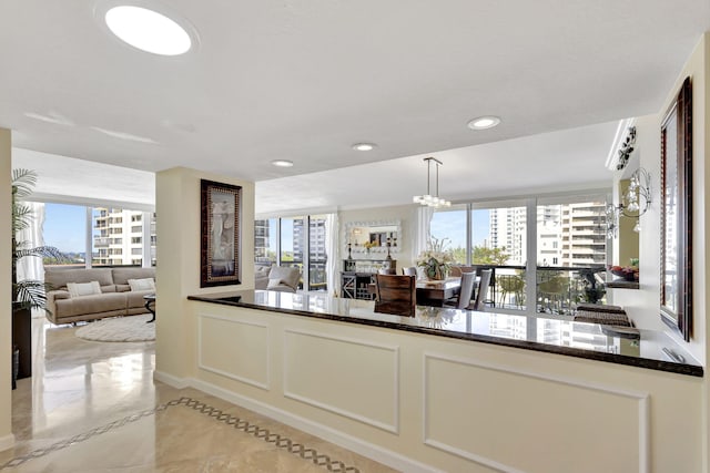 kitchen featuring dark stone counters, pendant lighting, a notable chandelier, white cabinetry, and light tile patterned flooring