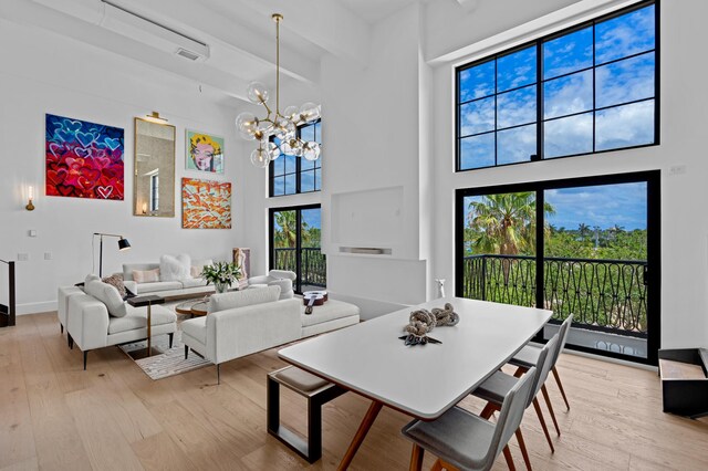 dining room with light hardwood / wood-style floors, a towering ceiling, and a chandelier