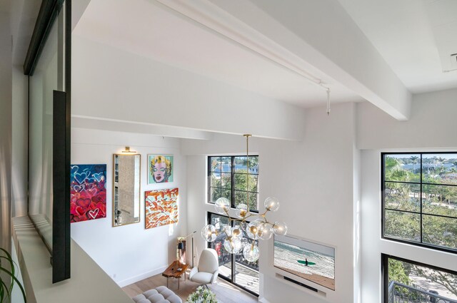 details with hardwood / wood-style flooring, beamed ceiling, and an inviting chandelier