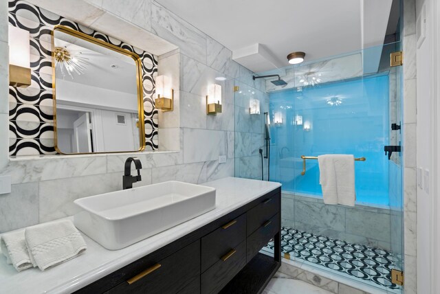 bathroom with tiled shower, vanity, and tile walls