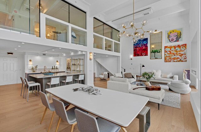 dining area featuring light hardwood / wood-style floors, a high ceiling, and a chandelier