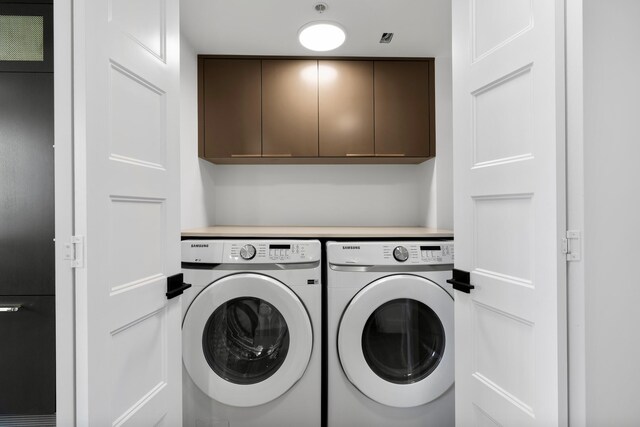 washroom featuring cabinets and washer and clothes dryer