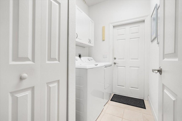 clothes washing area with cabinets, washing machine and clothes dryer, and light tile patterned flooring