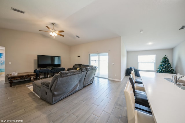 living room featuring lofted ceiling, a healthy amount of sunlight, light wood-type flooring, and ceiling fan