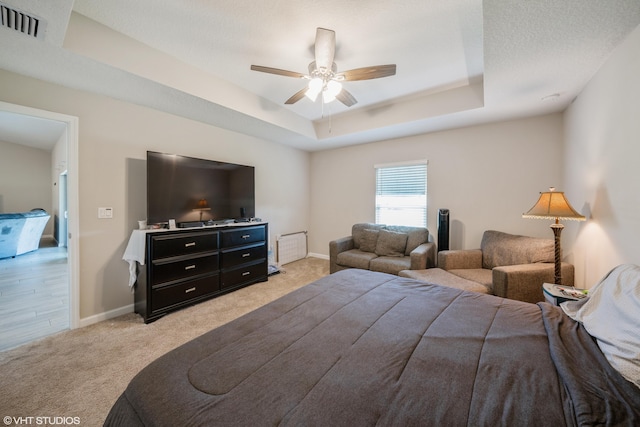 carpeted bedroom featuring a textured ceiling, a tray ceiling, and ceiling fan