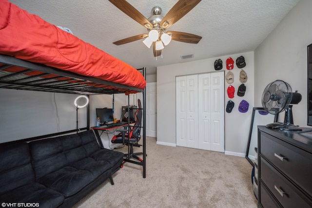 carpeted bedroom featuring ceiling fan, a closet, and a textured ceiling