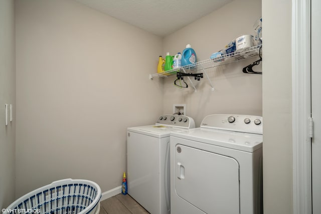 laundry area with hardwood / wood-style flooring, a textured ceiling, and washing machine and clothes dryer