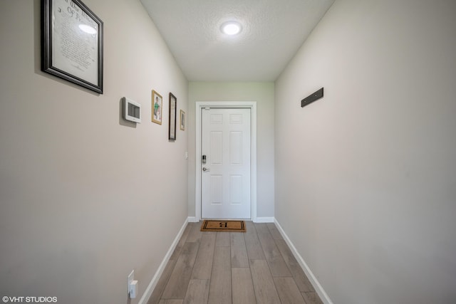 doorway to outside featuring light wood-type flooring and a textured ceiling