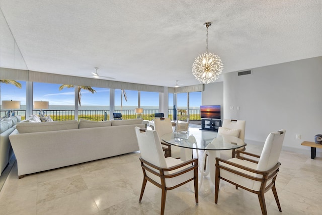 dining space featuring ceiling fan with notable chandelier and a textured ceiling