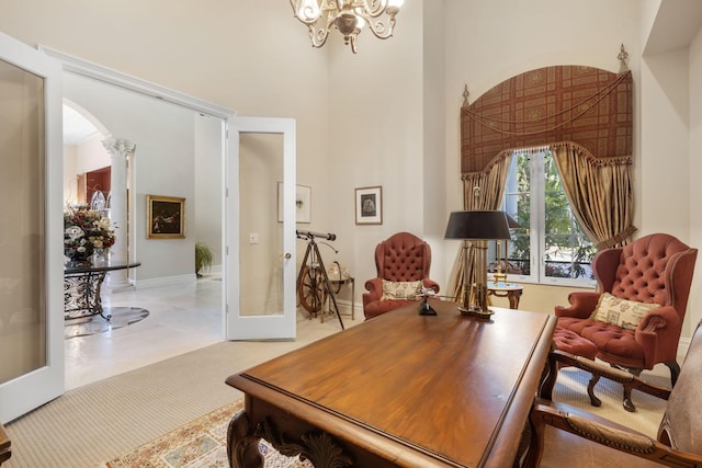 office area with french doors, a towering ceiling, decorative columns, and a notable chandelier