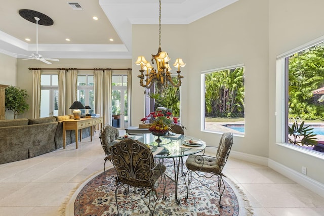 dining space with ceiling fan with notable chandelier, a tray ceiling, and ornamental molding