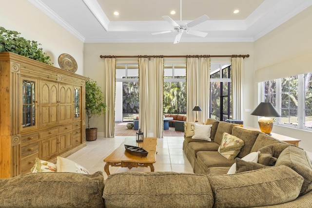 tiled living room with a raised ceiling, ceiling fan, and ornamental molding