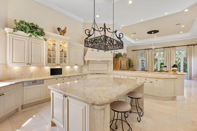 kitchen featuring a kitchen bar, light stone countertops, ceiling fan, cream cabinetry, and a kitchen island