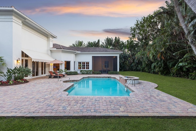 pool at dusk featuring french doors and a patio