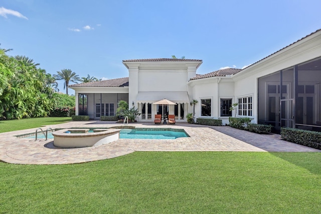 rear view of property featuring a lawn, a sunroom, a swimming pool with hot tub, and a patio