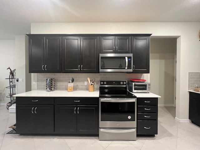 kitchen with backsplash, light tile patterned floors, and stainless steel appliances