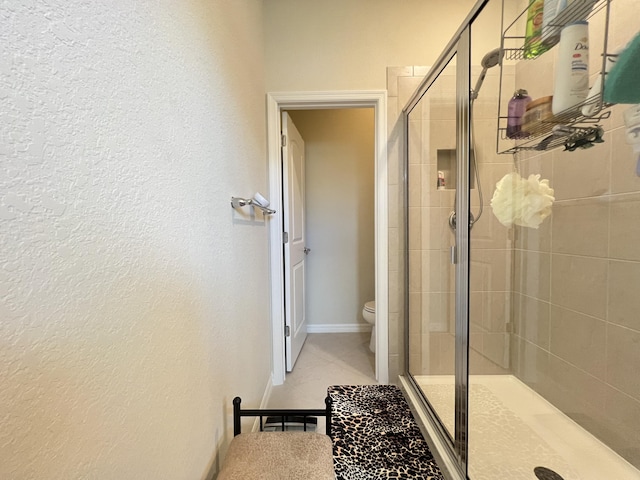 bathroom featuring toilet and a shower with shower door