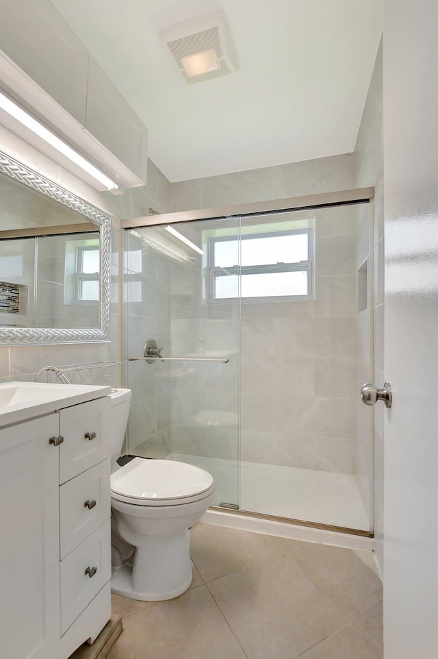 bathroom featuring toilet, vanity, tile patterned floors, and walk in shower