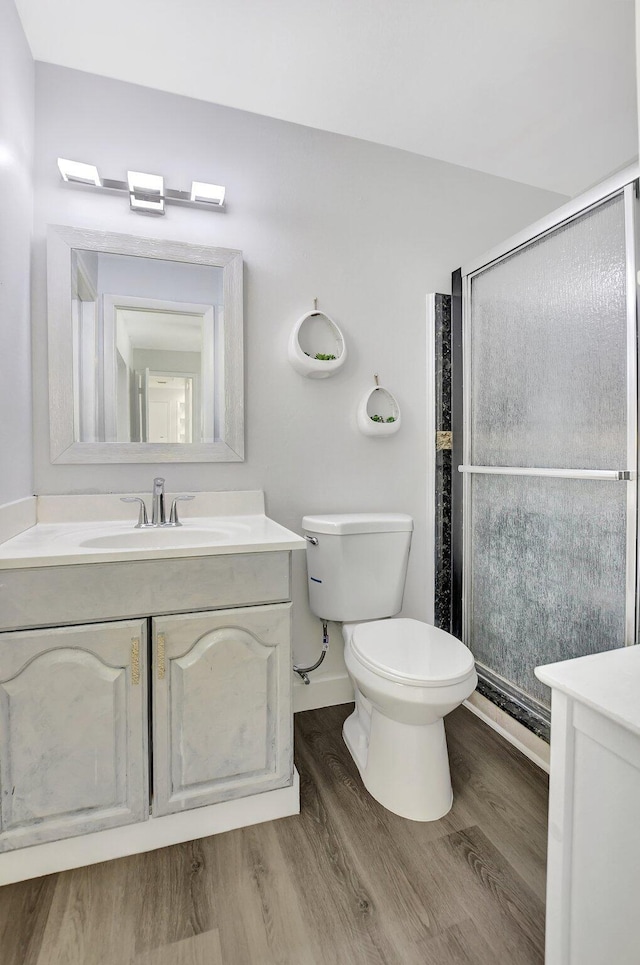 bathroom with hardwood / wood-style flooring, vanity, toilet, and a shower with door