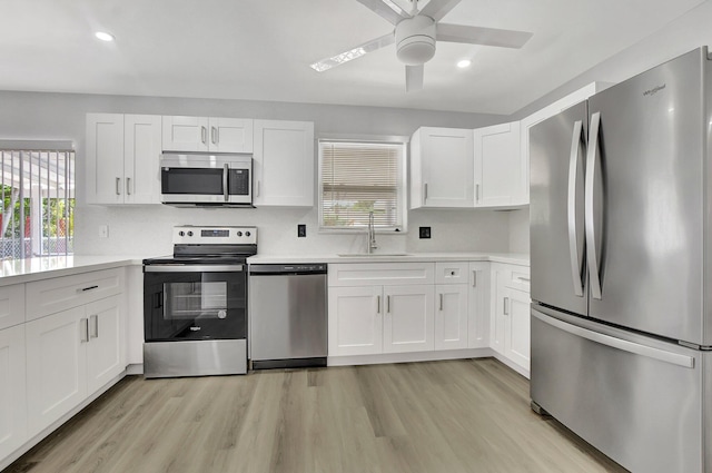 kitchen with white cabinetry, sink, ceiling fan, appliances with stainless steel finishes, and light wood-type flooring