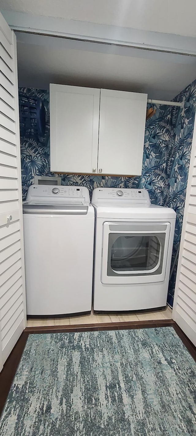 washroom featuring separate washer and dryer, cabinets, and wood-type flooring