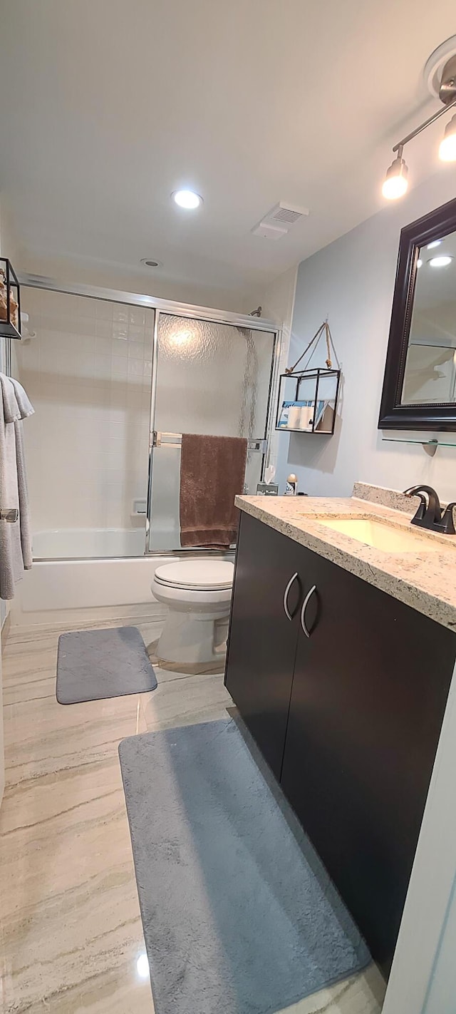 full bathroom featuring toilet, vanity, and shower / bath combination with glass door