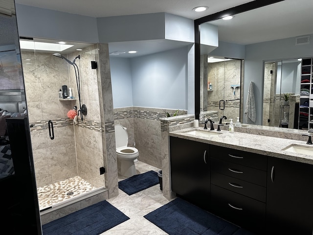 bathroom with tile walls, an enclosed shower, vanity, and toilet