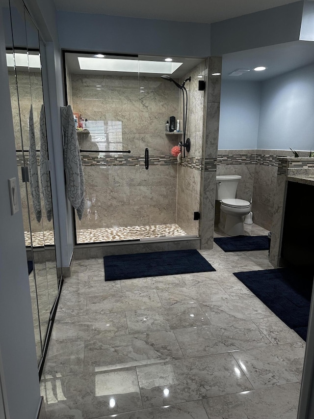 bathroom featuring a shower with shower door, tile walls, and toilet