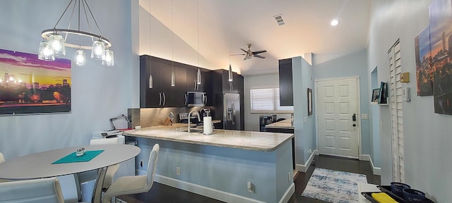 kitchen featuring tasteful backsplash, sink, kitchen peninsula, pendant lighting, and stainless steel appliances