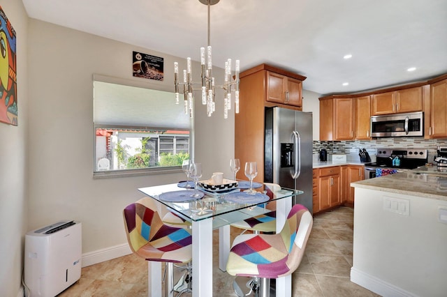 kitchen with appliances with stainless steel finishes, tasteful backsplash, light tile patterned floors, decorative light fixtures, and an inviting chandelier