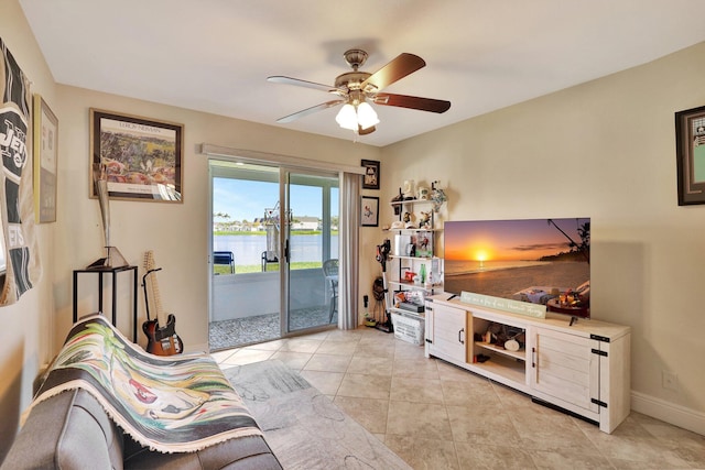 living area featuring tile patterned floors, a ceiling fan, and baseboards