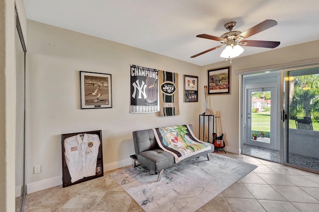 living area featuring ceiling fan, tile patterned floors, and baseboards