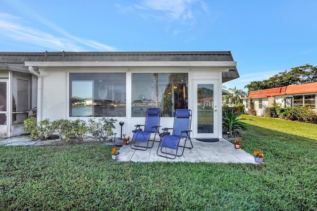 back of property featuring a sunroom, a yard, and a patio