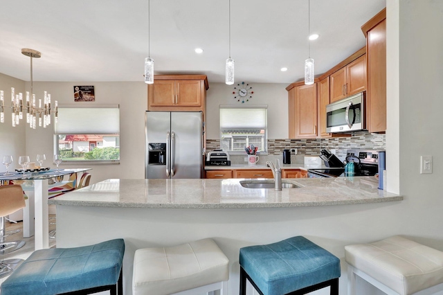 kitchen with sink, decorative light fixtures, a notable chandelier, kitchen peninsula, and stainless steel appliances