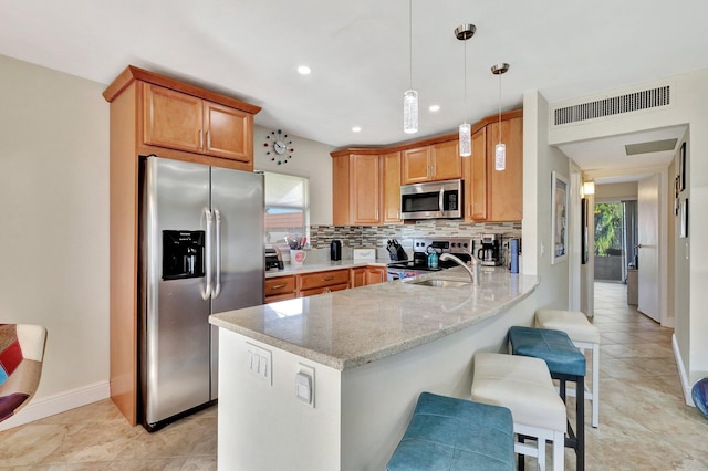 kitchen with a peninsula, a sink, visible vents, appliances with stainless steel finishes, and decorative backsplash