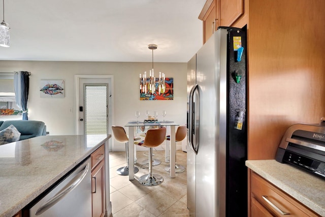 kitchen featuring brown cabinets, light tile patterned floors, stainless steel appliances, light countertops, and hanging light fixtures