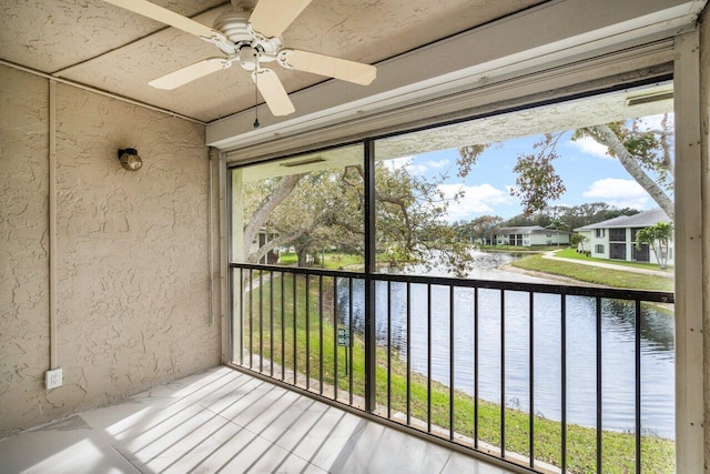 unfurnished sunroom featuring a water view and ceiling fan