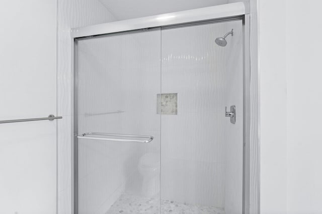 bathroom featuring toilet and a shower with shower door