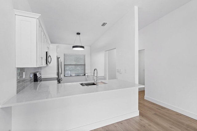 kitchen with sink, hanging light fixtures, kitchen peninsula, white cabinets, and appliances with stainless steel finishes