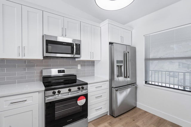 kitchen featuring backsplash, light stone counters, stainless steel appliances, light hardwood / wood-style flooring, and white cabinets