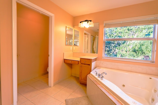 bathroom with tile patterned floors, vanity, a relaxing tiled tub, and toilet