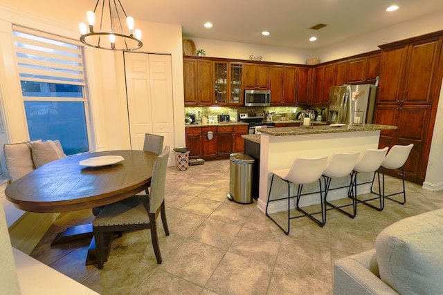 kitchen featuring a notable chandelier, stainless steel appliances, hanging light fixtures, and an island with sink