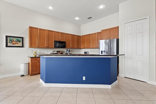 kitchen with a center island with sink, light tile patterned flooring, and stainless steel appliances