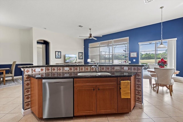 kitchen with an island with sink, stainless steel dishwasher, hanging light fixtures, and sink