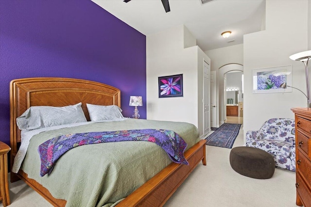 bedroom with ensuite bathroom, ceiling fan, and light carpet