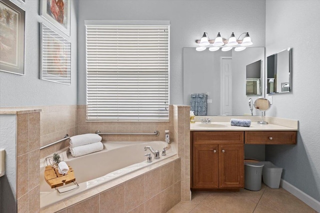 bathroom with tiled tub, tile patterned flooring, vanity, and a healthy amount of sunlight