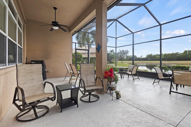 view of patio featuring a water view, glass enclosure, and ceiling fan