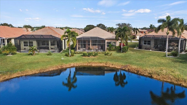 rear view of house with a lanai, a lawn, and a water view