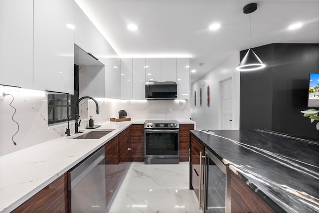 kitchen with sink, light stone counters, decorative light fixtures, stainless steel appliances, and white cabinets