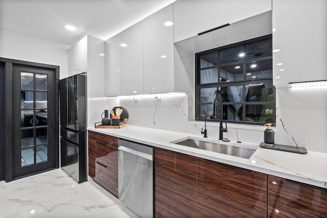 kitchen featuring dishwasher, black fridge, sink, and white cabinets